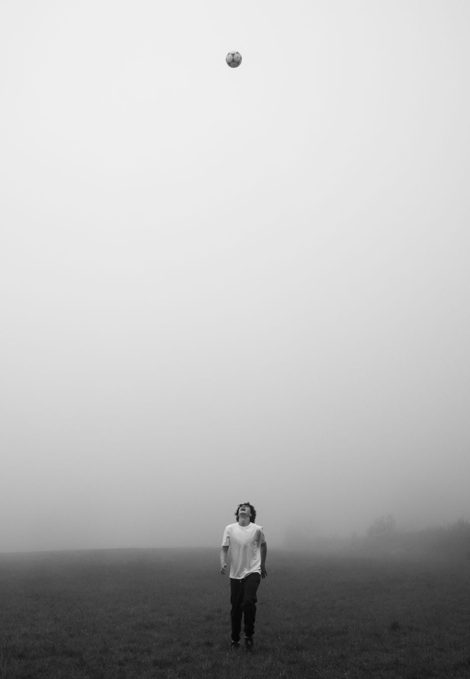 A teenager standing on a patch of grass at the bottom of the screen. At the very top: a football, sorrounded by thick fog.